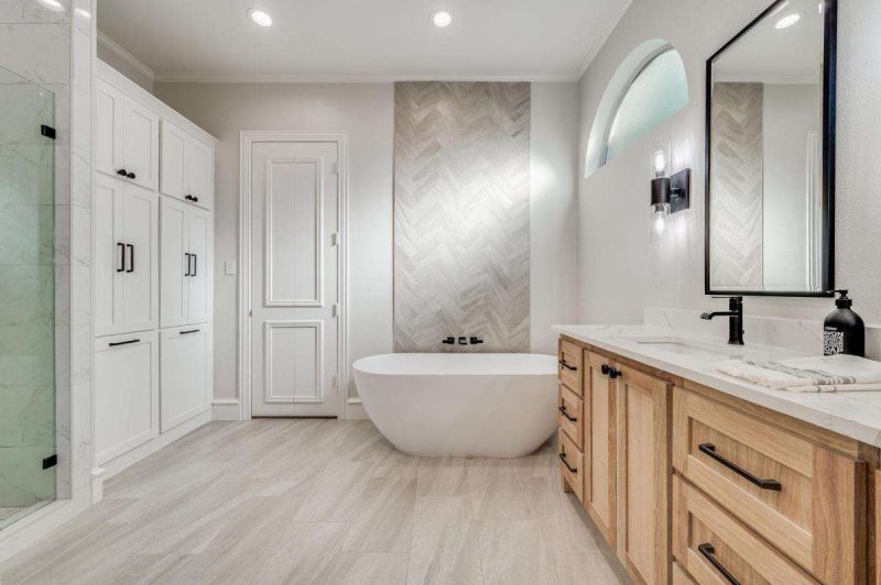 Modern bathroom by Make Ready Home with freestanding tub, wood vanity, and herringbone tile accent wall.