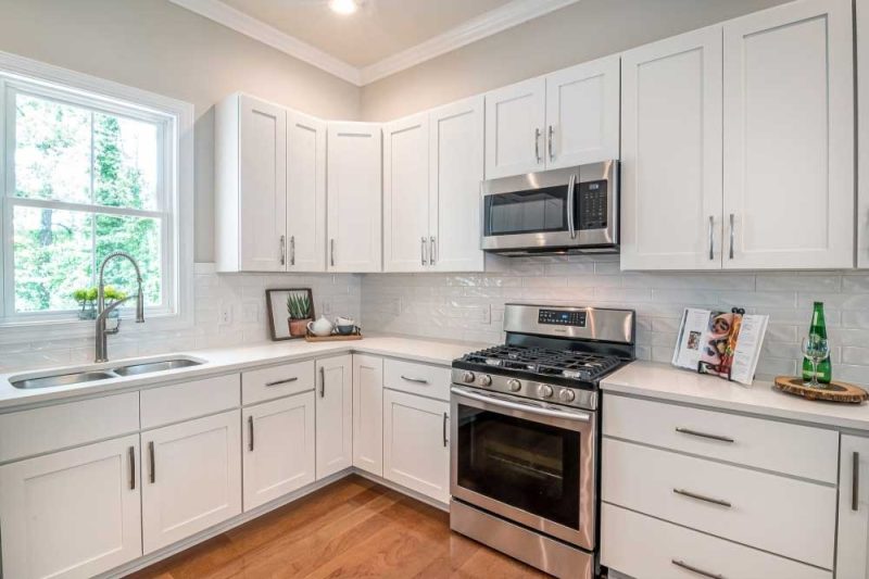 Make Ready Home cabinet painting or replacement in Dallas kitchen with bright white cabinets, stainless steel appliances, and wood floors.
