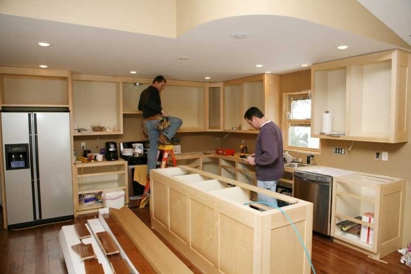 Kitchen renovation with wood cabinets being installed and appliances in place.
